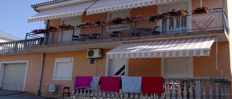 A two-story building with balconies, outdoor seating, and laundry hanging.