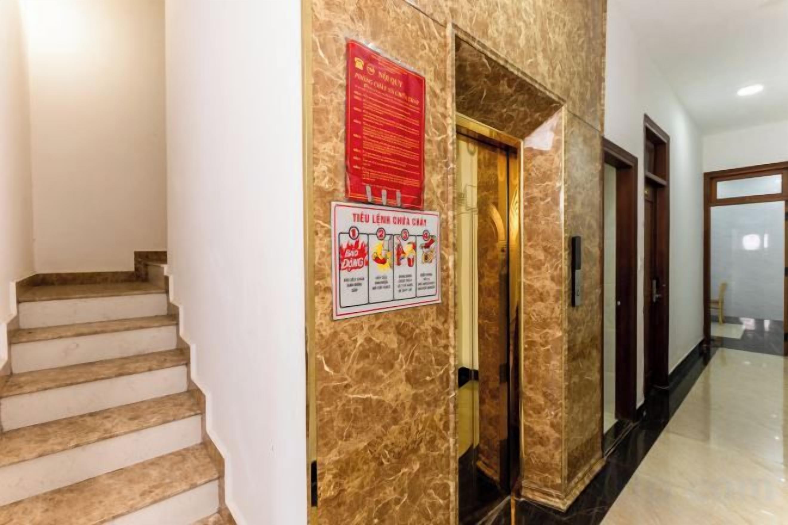 Un pasillo de hotel con una pared de mármol, una escalera y una puerta que da a otra habitación.