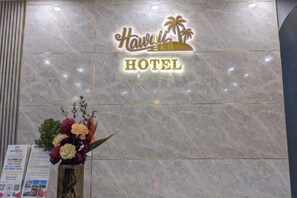 A reception area with a marble wall, a sign reading 'Hawai'i Hotel', and a floral arrangement. - Hawaii Hotel Dalat (Dalat)