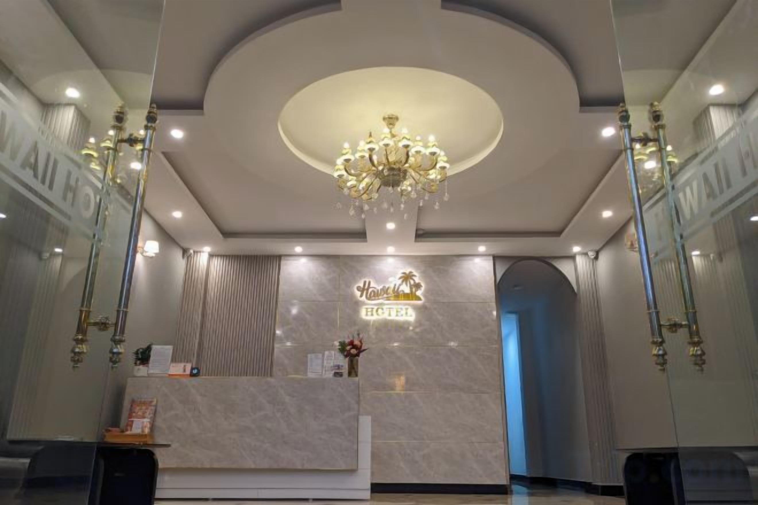 A hotel reception area with a marble counter, a chandelier, and a sign that reads 'Hotel'.