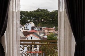 A view from a balcony with a metal railing, overlooking a residential area with houses and trees. - Hawaii Hotel Dalat (Dalat)