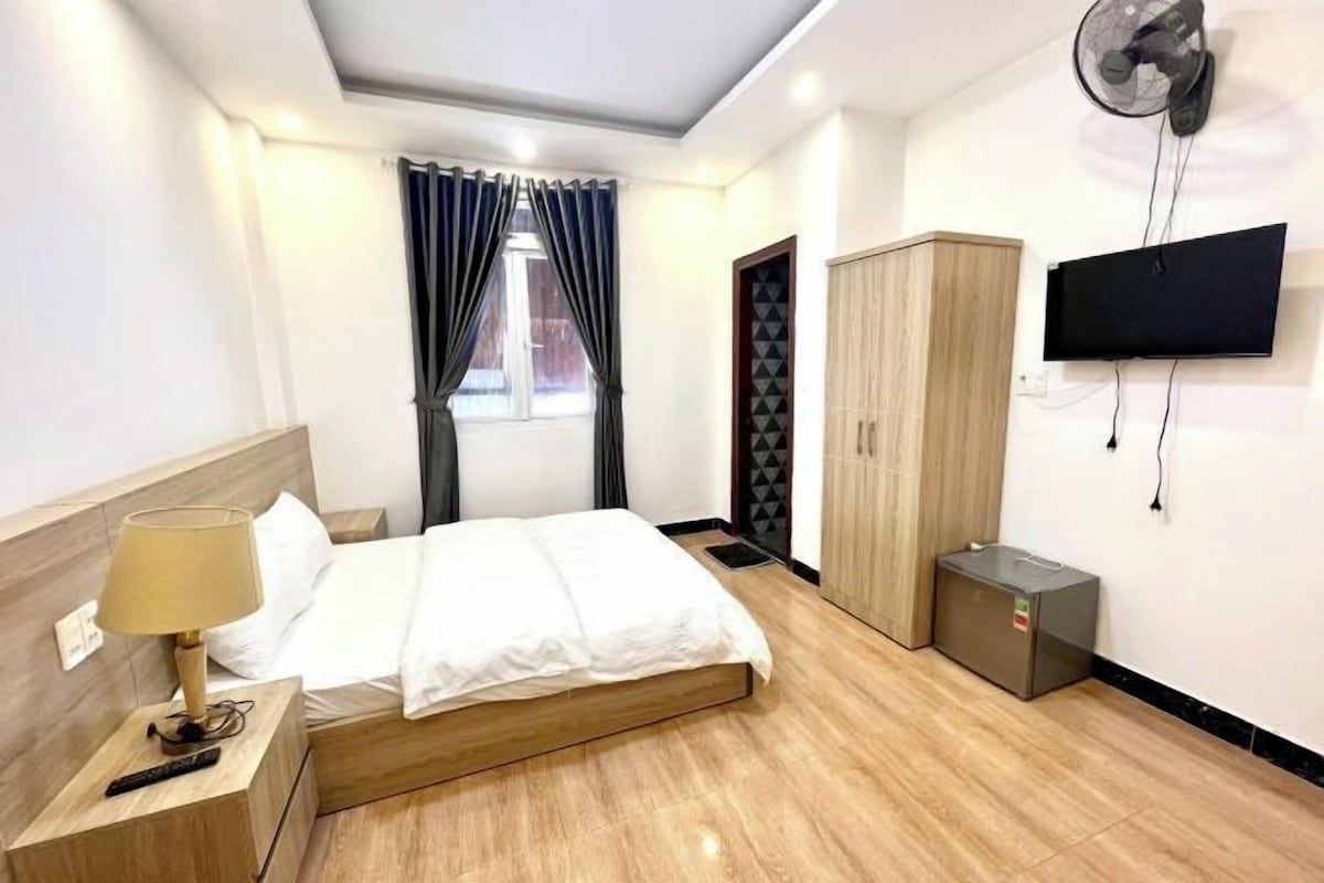Una habitación de hotel con cama, televisión, armario y una pequeña alacena.