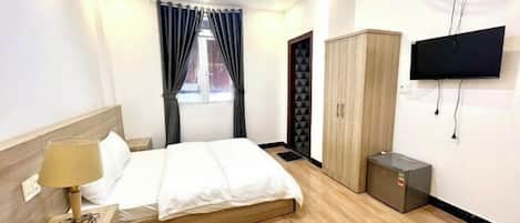 A hotel room with a bed, a TV, a wardrobe, and a small cabinet.