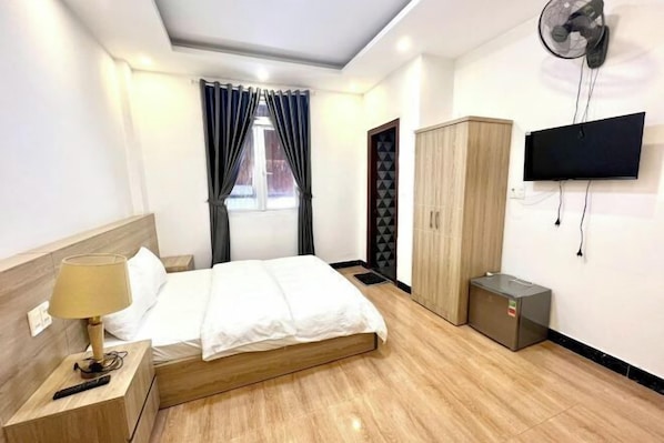 Una habitación de hotel con cama, televisión, armario y una pequeña alacena.