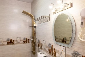 Un baño con ducha, lavabo, espejo y jarrones decorativos en la pared.