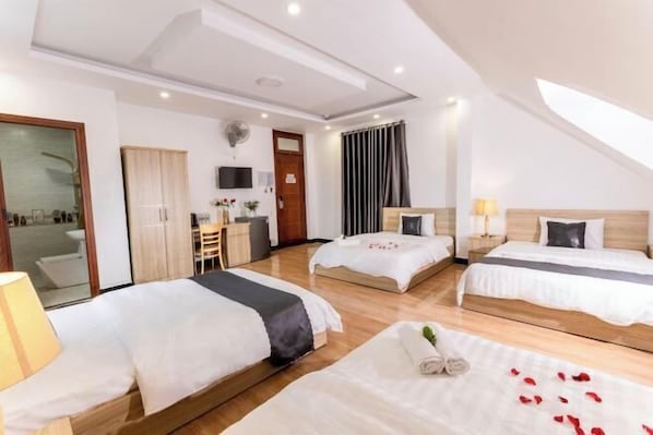 Habitación de hotel con dos camas, un escritorio, una silla, un televisor y un amplio ventanal con cortinas.