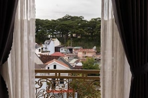 Vista desde un balcón con barandilla de hierro forjado, sobre un barrio residencial con varios edificios y árboles.