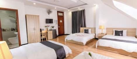 A hotel room with two beds, a desk, a chair, and a shower area.