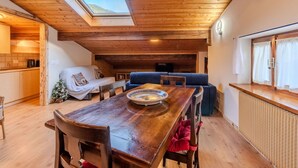 Ein gemütlicher Essbereich mit Holzboden, einem Tisch und Stühlen, einer Couch und einem Oberlicht.