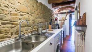 A kitchen with a stone wall, a washing machine, and a radiator.