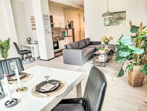 A modern living room with a grey sofa, a dining table set for two, and a kitchen in the background. - Lovely apartment for 4 people with WIFI, TV, terrace, pets allowed and panoramic view (Beverungen)