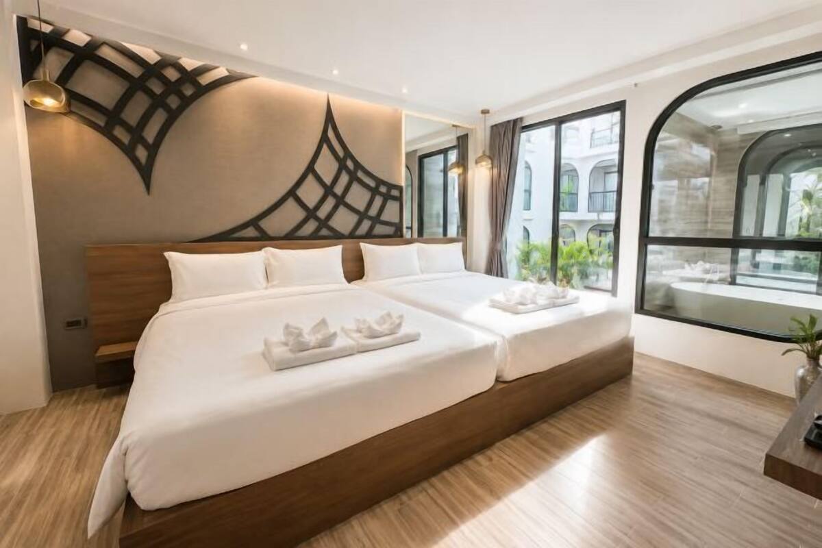 A modern hotel room with a large bed, a decorative wall, and a view of the outside.