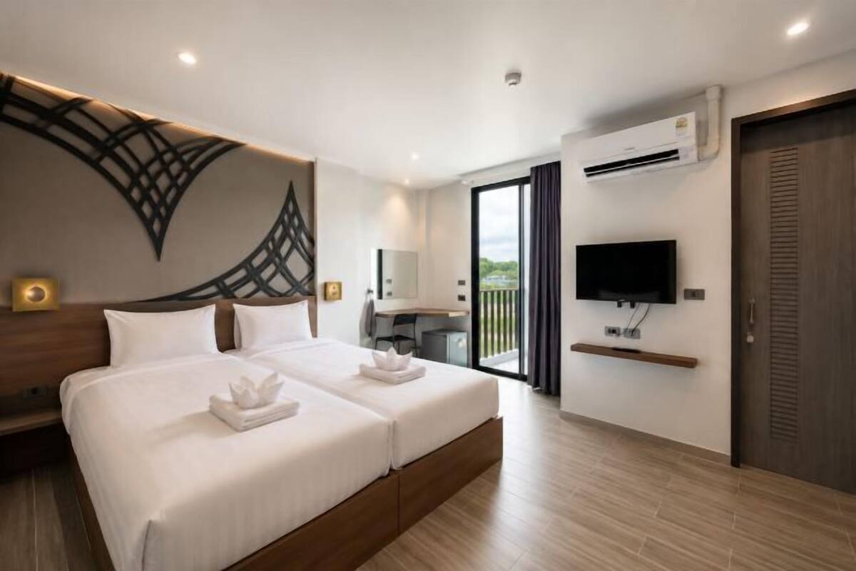 A modern hotel room with a large bed, a desk, a flat-screen TV, and a balcony.