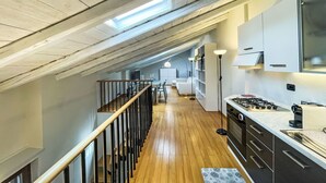 A modern kitchen with a skylight, wooden flooring, and a view of the living area.