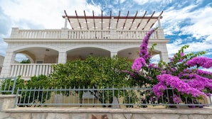A white building with a covered porch and stone walls.