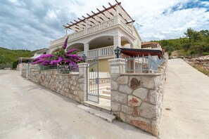 A two-story building with a stone facade, a balcony with a pergola, and a stone wall with a gate. - Modern Villa with Pool (Blato)