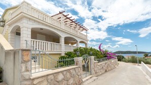 A two-story building with a balcony, stone walls, and a view of the sea.