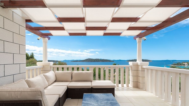 A covered outdoor seating area with a view of the sea.