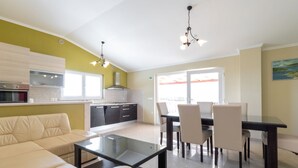 A modern kitchen with a dining area, a sofa, and a table.