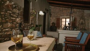 Habitación con paredes de piedra y una mesa dispuesta para dos, con dos copas de vino y una botella.