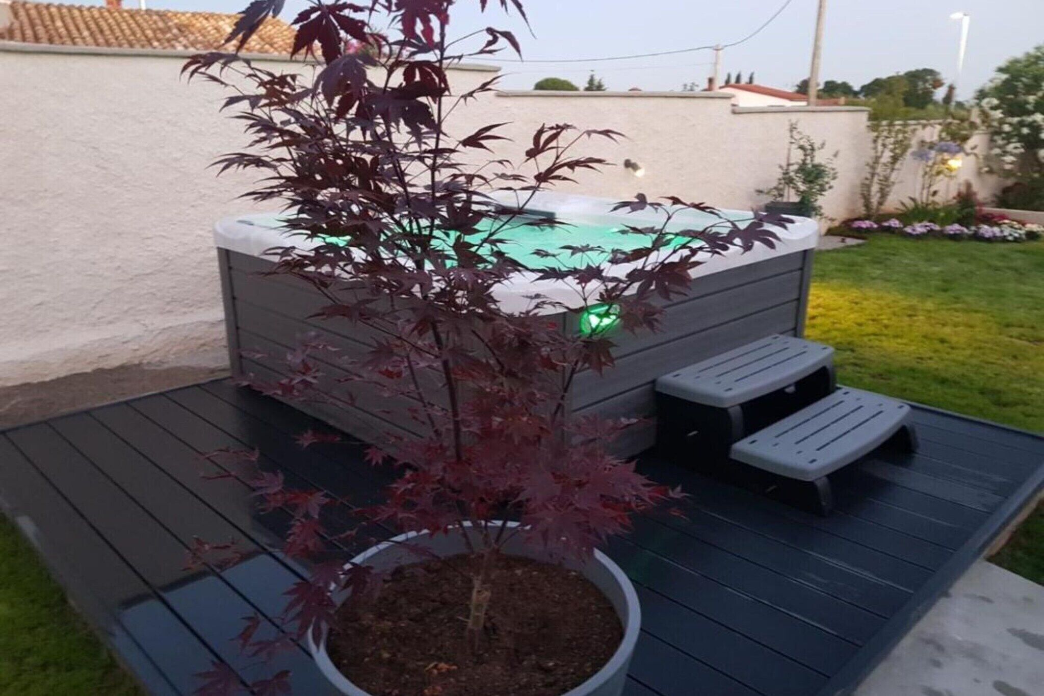 Un jacuzzi en una terraza con una planta en maceta al frente.