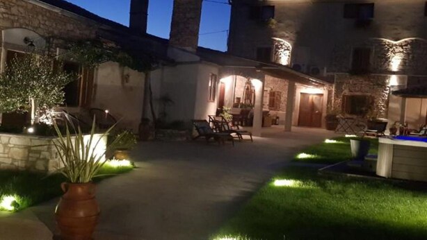 Un patio con muros de piedra, un área de descanso y un espacio al aire libre bien iluminado.