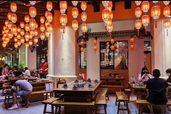 A restaurant with wooden tables and benches, hanging lanterns, and a traditional interior design.