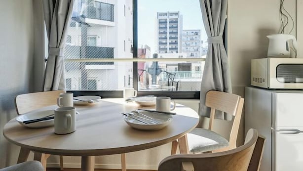 A dining area with a round table, chairs, a white kettle, and a white microwave. - Mi-HOTEL ASAKUSA (Tokyo)