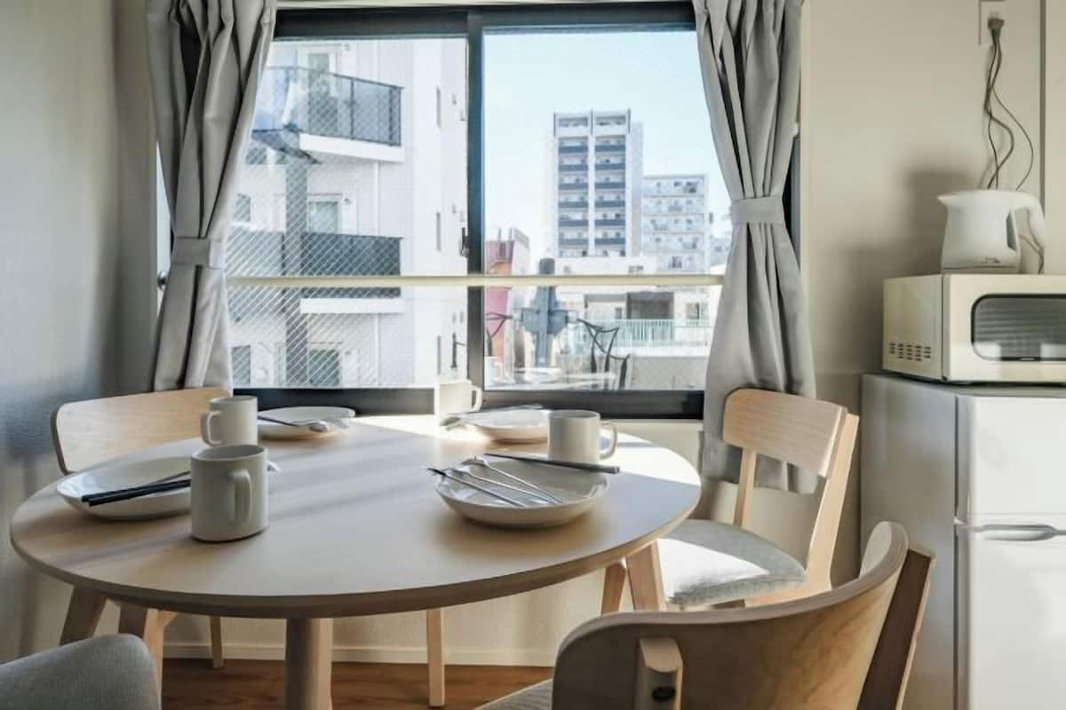 A dining area with a round table, chairs, a white kettle, and a white microwave.