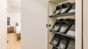 A hotel room with a built-in shoe rack holding multiple pairs of slippers. - Mi-HOTEL ASAKUSA (Tokyo)