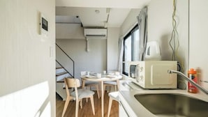 A compact kitchen with a microwave, sink, and dining area with chairs. - Mi-HOTEL ASAKUSA (Tokyo)