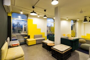 Un intérieur moderne offrant différents types de sièges, notamment un canapé, des fauteuils et un banc. De grandes fenêtres permettent d’admirer la vue sur la ville.