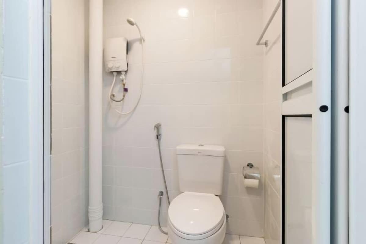 Une petite salle de bain moderne équipée d’un WC, d’une douche et d’un porte-rouleau de papier toilette.