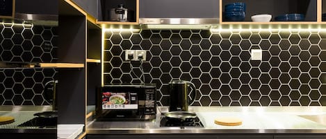 A modern kitchen with black cabinets, a hexagonal tile backsplash, and a built-in induction cooktop.