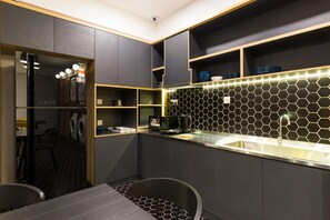 Une cuisine moderne équipée d’un lave-linge intégré, d’un évier et d’un coin repas avec une table et des chaises.