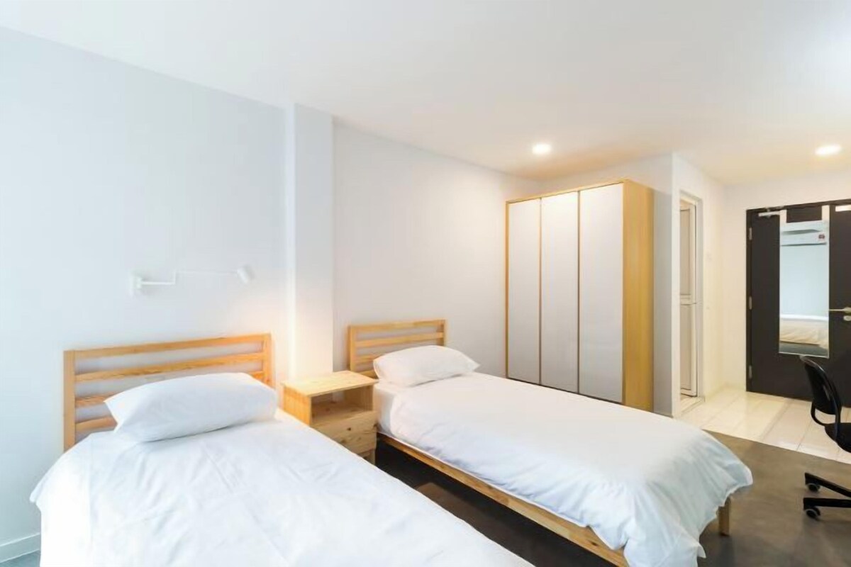 A bedroom with two single beds, a wardrobe, and a desk.