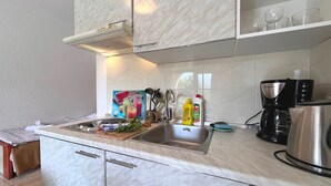 A kitchen with a marble countertop, stainless steel sink, and a coffee maker. - Apartments Butković - One Bedroom Apartment (A2) (Novi Vinodolski)