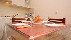 A dining table set with plates, glasses, a basket of bread, and a napkin. - Apartments Butković - One Bedroom Apartment (A2) (Novi Vinodolski)