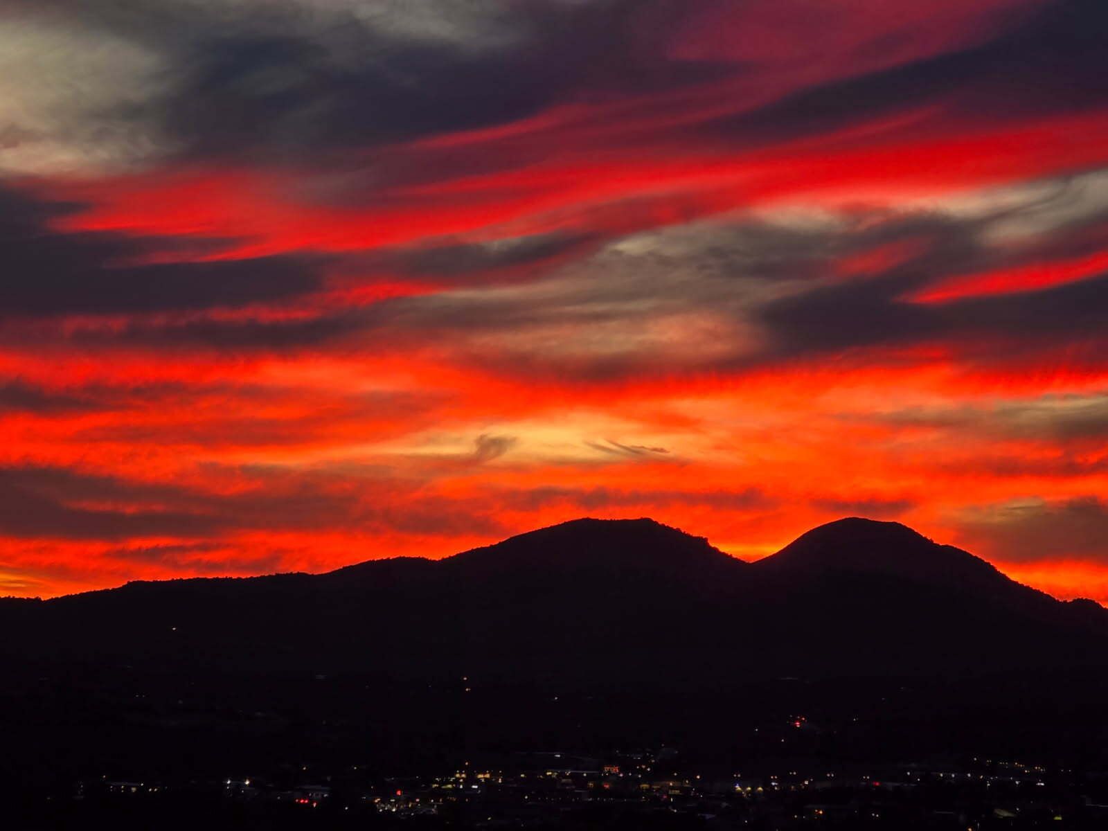 A mountain range silhouette against a vibrant sunset sky.