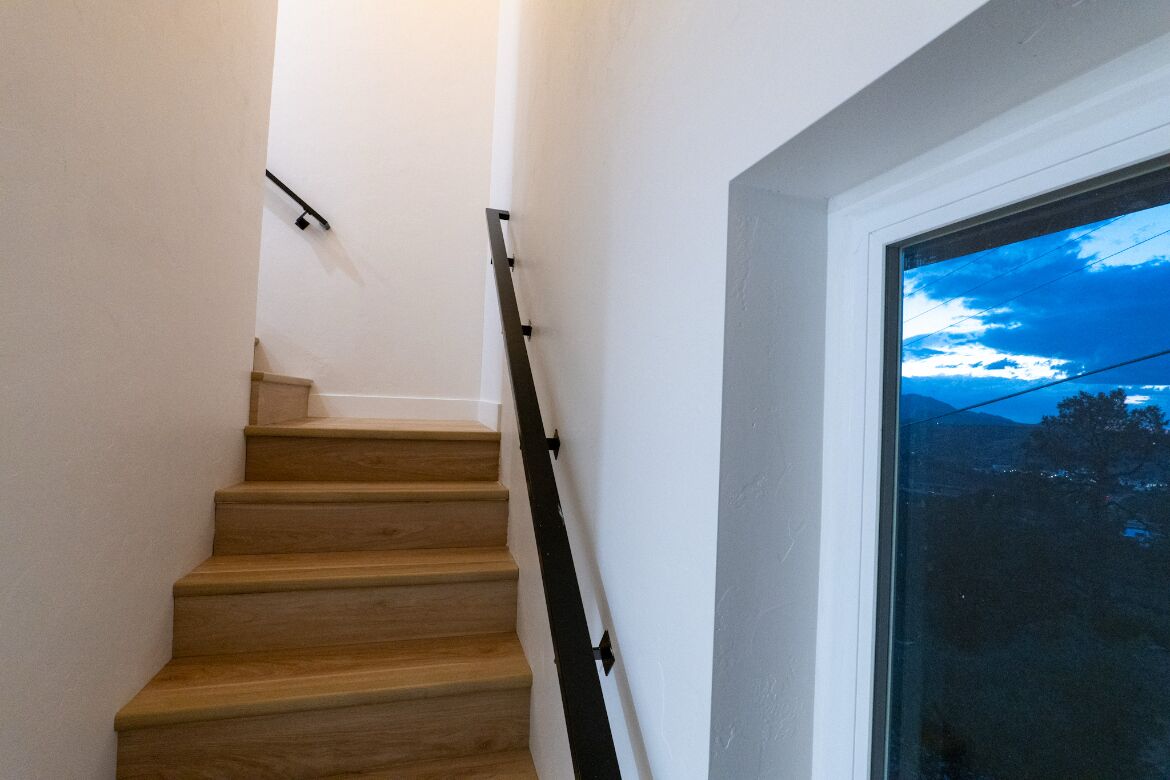A wooden staircase with a handrail, leading to a landing.