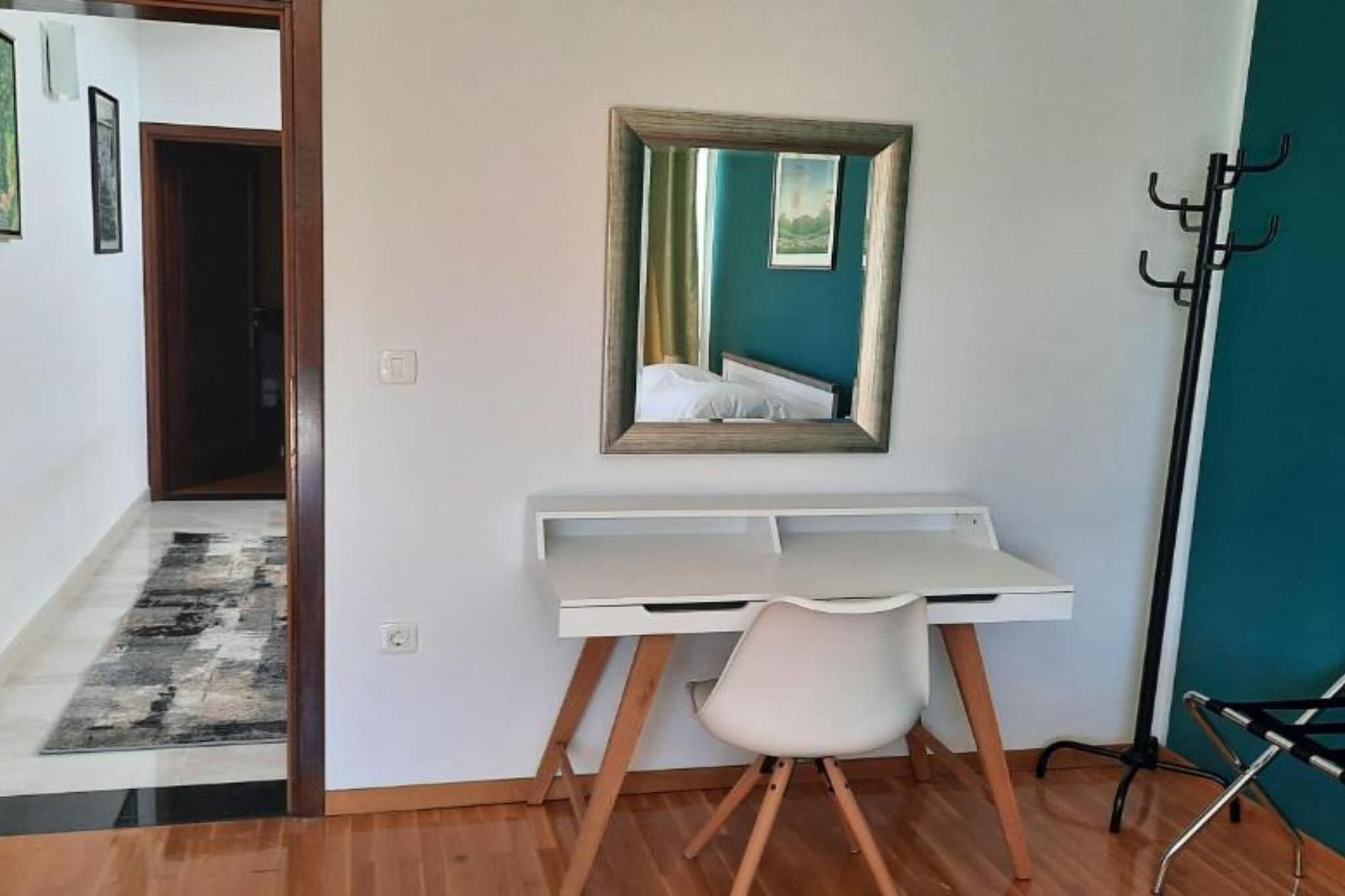 A room with a desk, chair, and a mirror on the wall.