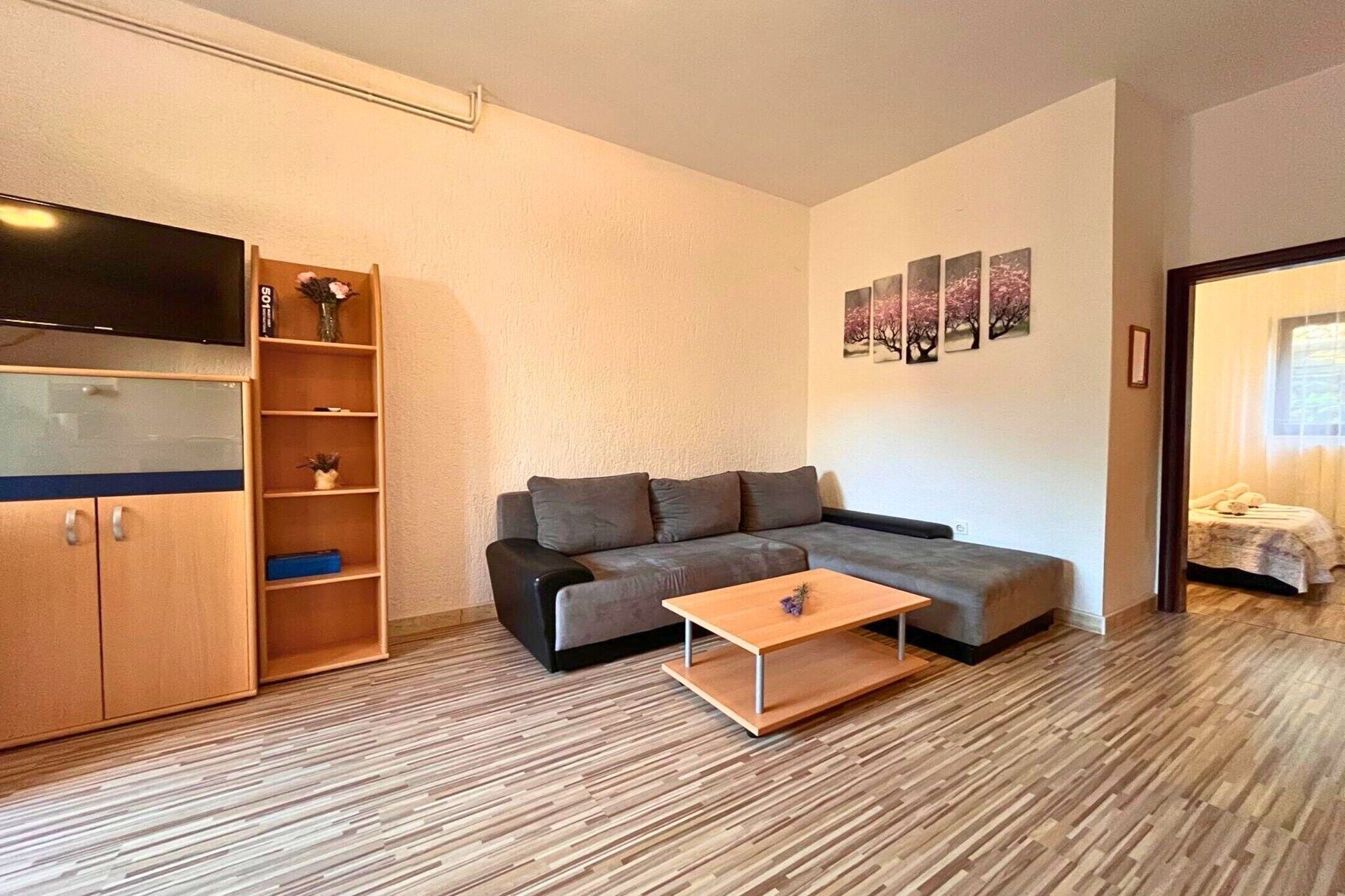 Moderni olohuone, jossa on sohva, sohvapöytä, televisio ja kirjahylly.
