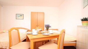 Ein kleiner, gemütlicher Raum mit einem Holztisch, der für das Frühstück gedeckt ist, zwei Einzelbetten und einem Blumentopf.