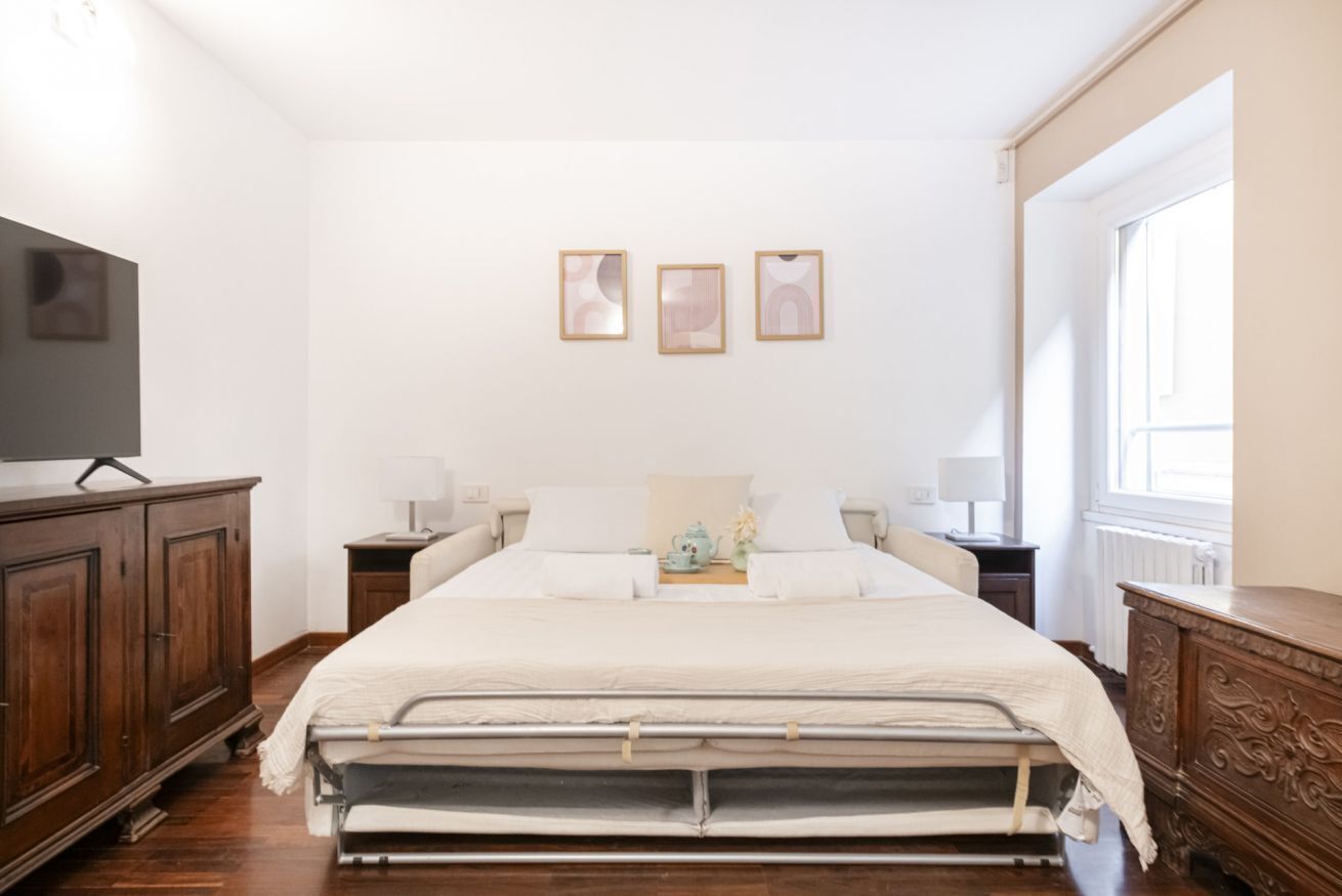 Une chambre à coucher bien rangée, avec un lit, des tables de chevet, une commode et un téléviseur.