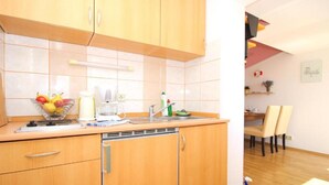 Cocina compacta con armarios de madera, un lavamanos y una encimera con un frutero y una cafetera.
