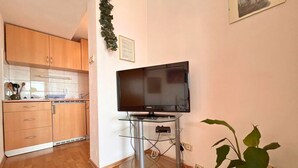 Una cocina compacta con armarios de madera y un mueble de televisión de vidrio.