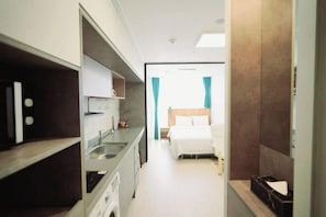 A compact hotel room with a kitchenette, a bed, and a bathroom. - Well Stay Hotel (Incheon)