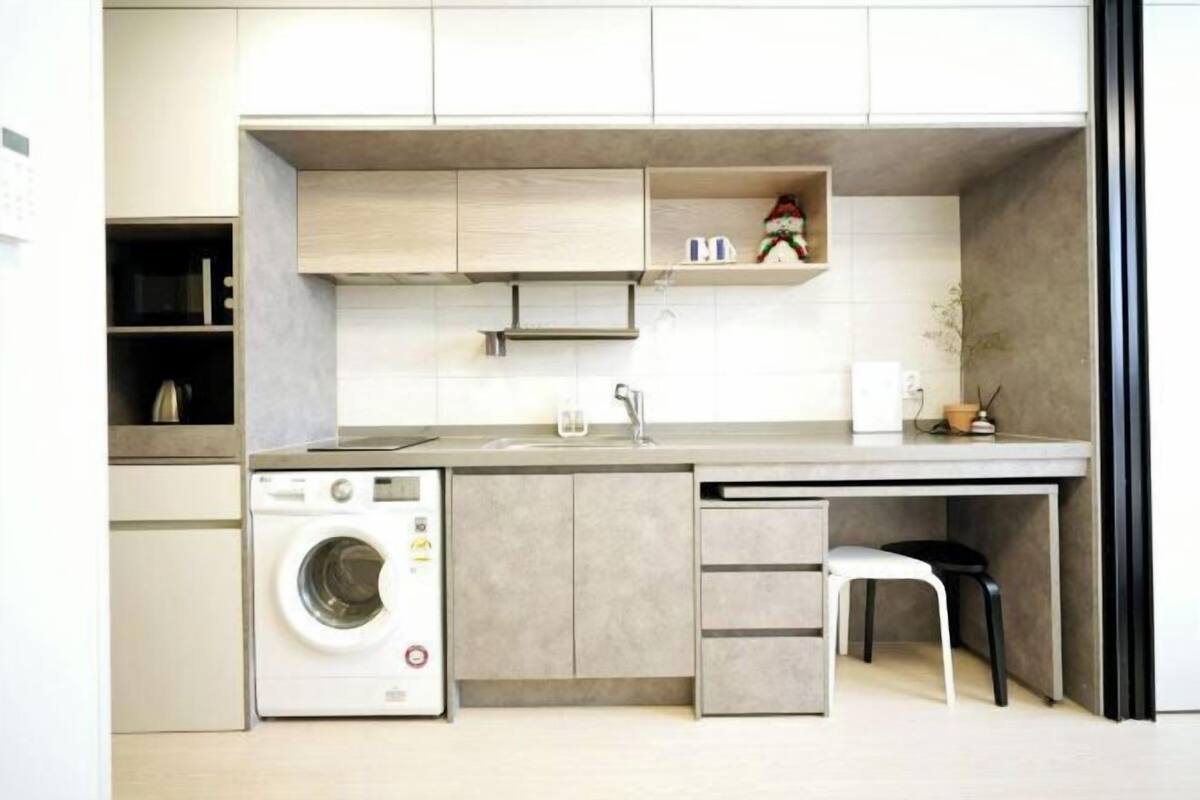 A compact kitchen with a washing machine, a sink, and a small dining area.