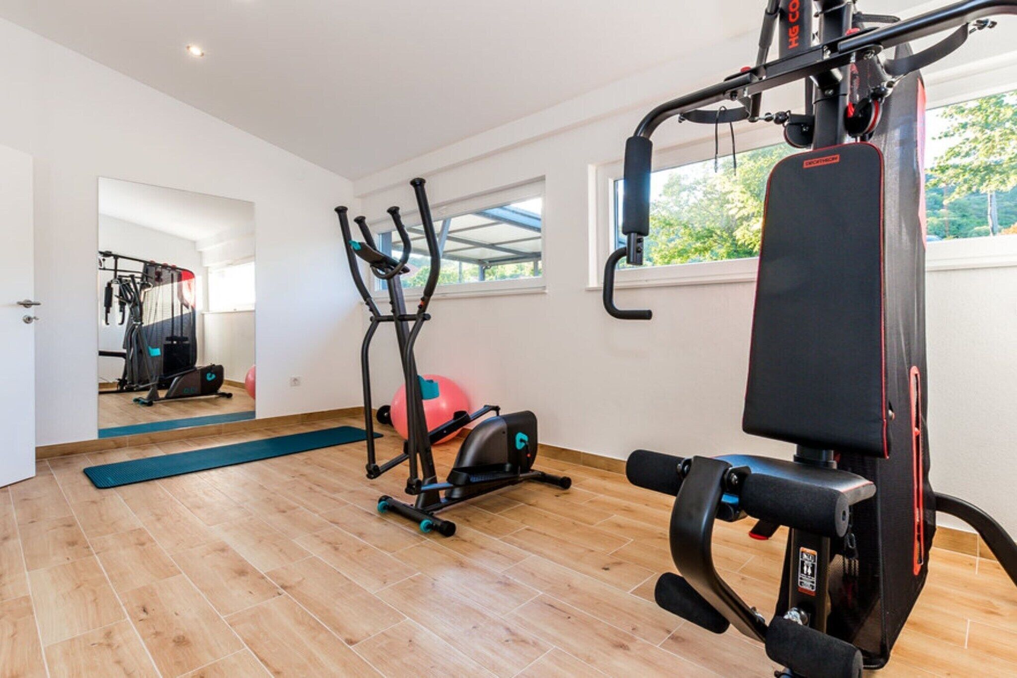 Un gimnasio con equipo de ejercicio, un ventanal grande y suelo de madera.
