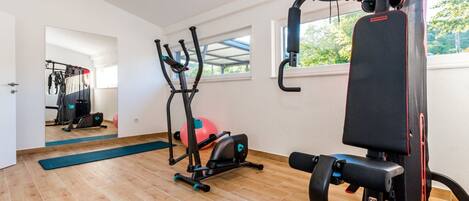 Un gimnasio con equipo de ejercicio, un ventanal grande y suelo de madera.